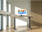 Ein Holztisch mit elektrisch höhenverstellbarem Gestell, einem Monitor und einer Tastatur.