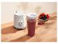 Weißer Personal Blender mit rotem Fruchtsmoothie und einer Schale Beeren auf einem Holztisch.