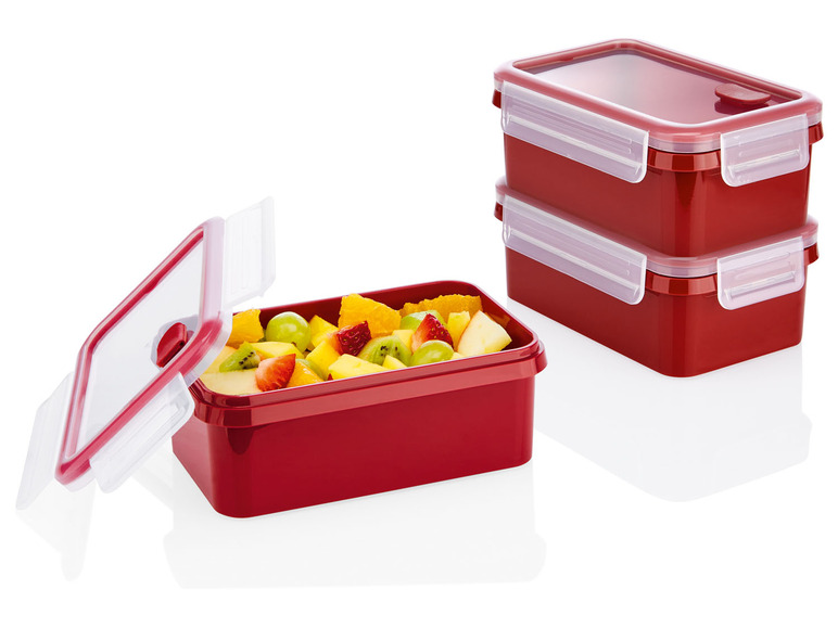 Drei rote Plastik-Lunchboxen mit Obst.