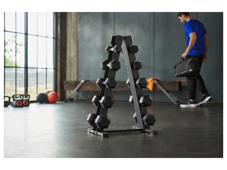 Ein Fitnessstudio mit Hantelständer, Kettlebells und Bällen, mit einem Mann, der eine Sporttasche trägt.