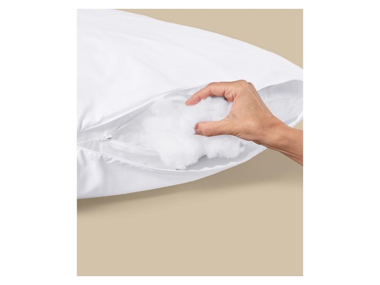 Hand greift Baumwollfüllung aus einem weißen Kissen mit Reißverschluss.
