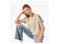 Frau in hellbeigem T-Shirt mit Stickerei und hellblauer Jeans
