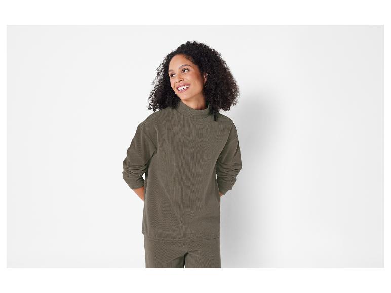 Eine Frau trägt eine dunkelgrüne Cordhose und ein Cordoberteil.