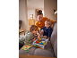 Eine Mutter und ihre Kinder spielen ein Kinderbrettspiel auf dem Sofa.