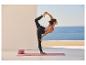 Frau in Yogapose auf einer Matte mit Yogablöcken, mit Meerblick.