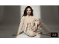 Frau in einem beigen dreiteiligen Loungewear-Set auf dem Boden sitzend
