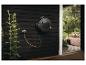 Automatischer Gartenschlauchaufroller an dunkler Holzwand, mit angeschlossenem Schlauch.