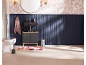 Badezimmer mit schwarzem Waschtisch, Toilette, floralem Teppich und marineblauer Paneelwand.