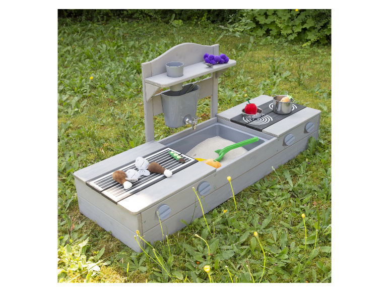 Kinder-Spielküche aus Holz mit Grill und Sandkasten im Rasen.