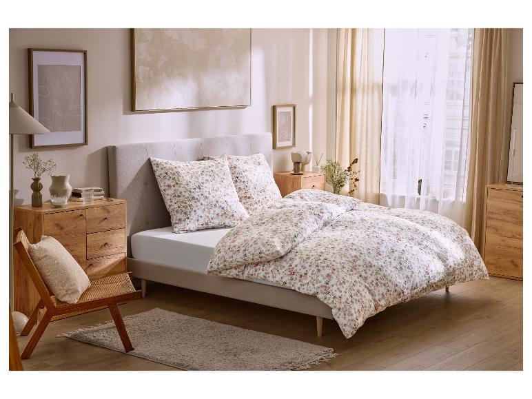 Schlafzimmer mit floraler Bettwäsche, Holzmöbeln und Kunstwerken