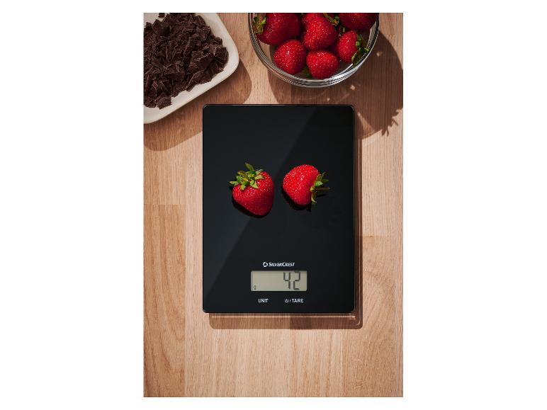 SilverCrest Küchenwaage wiegt zwei Erdbeeren, mit Schokolade und weiteren Erdbeeren daneben.