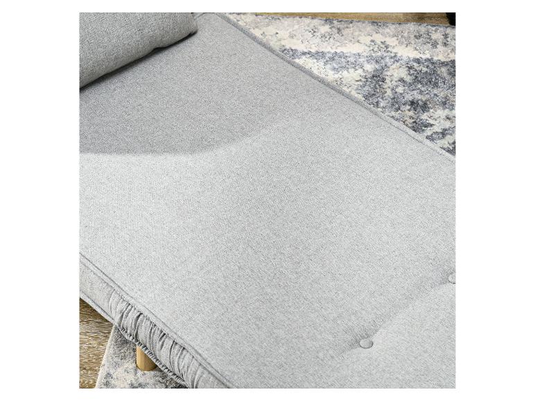 Hellgraues Sofa mit Kissen und Knöpfen auf einem gemusterten Teppich.