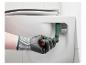 Hand in Arbeitshandschuh verwendet einen Toilettensitzschlüssel zur Montage eines Toilettensitzes.