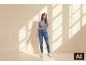 Frau in grauem Rollkragenpullover und Jeans steht vor einer Wand mit Schatten.