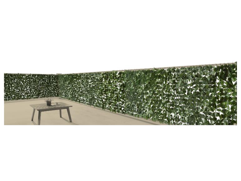 Künstlicher Blätterzaun mit Gartentisch und Vase auf einer Terrasse.
