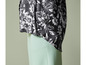 Eine schwarze Bluse mit weißem Blumenmuster und eine hellgrüne Hose.