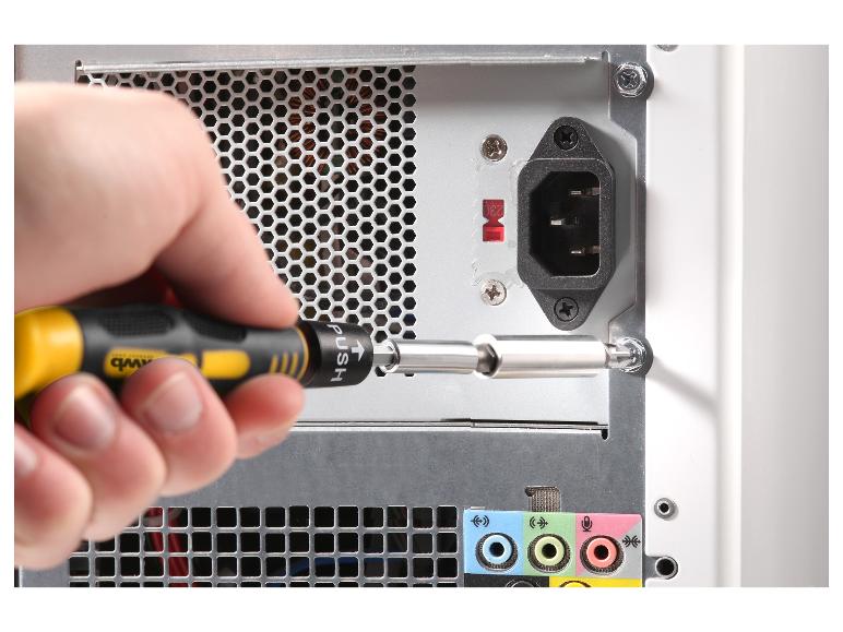 Person schraubt eine Schraube von der Rückseite eines Computers mit einem Schraubendreher ab.
