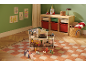 Puppenhaus mit Möbeln und Puppen auf einem karierten Teppich im Kinderzimmer.
