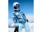 Frau in blauer Skibekleidung und Helm auf einem verschneiten Berg.