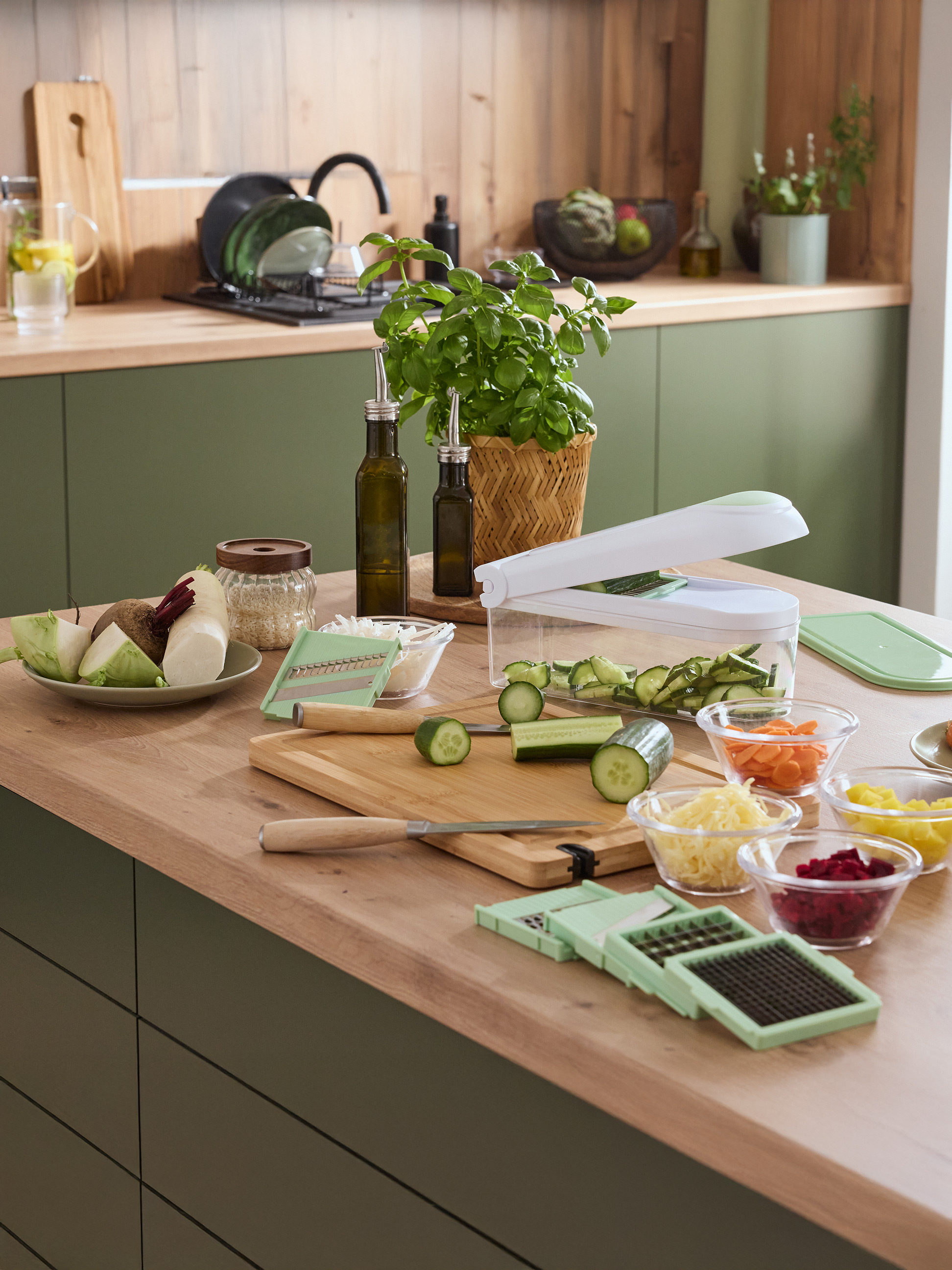 Küchenarbeitsplatte mit Gemüseschneider, frischem Gemüse und Kräutern.