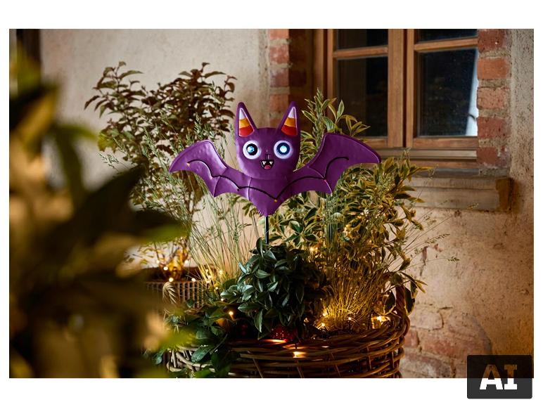Halloween-Gartendeko in Form einer lila Fledermaus in einem Blumentopf. [KI-generiertes Bild]