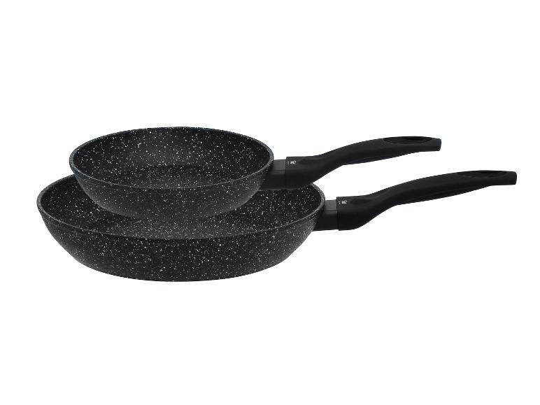 Zwei schwarze, gesprenkelte Bratpfannen mit Griffen, übereinander gestapelt.