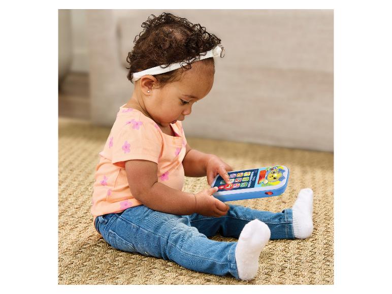 Baby sitzt auf dem Boden und spielt mit einem interaktiven Smartphone.