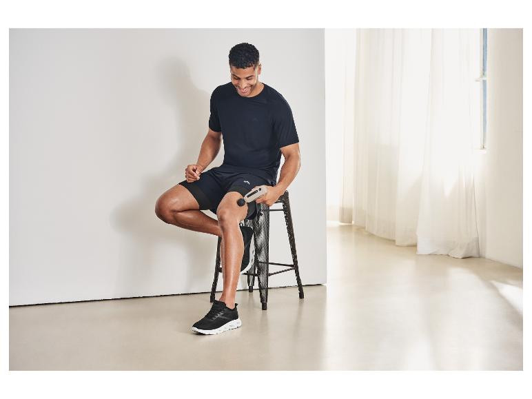 Mann in CRIVIT Sportshorts benutzt eine Massagepistole.