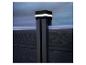 Beleuchteter Zaunpfosten mit dunklen Holzpaneelen und hellem Himmel im Hintergrund.