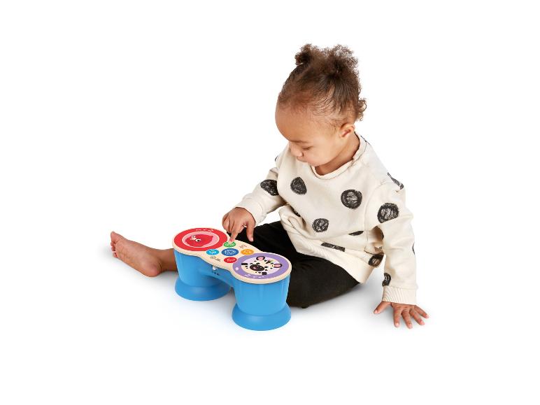 Ein Baby spielt mit einem blauen und roten Spielzeugschlagzeug auf weißem Hintergrund.