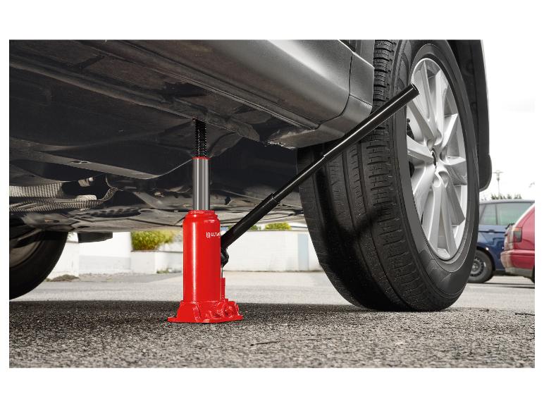 Roter Hydraulikwagenheber unter einem grauen Auto, das es leicht vom Boden hebt.