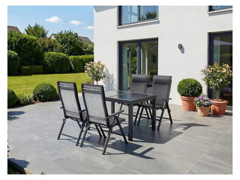 Gartenmöbel-Set auf der Terrasse: Tisch und vier Stühle, umgeben von Grün.