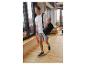 Mann in weißem T-Shirt, grauen Shorts und blauen Sneakern, trägt eine schwarze Sporttasche.