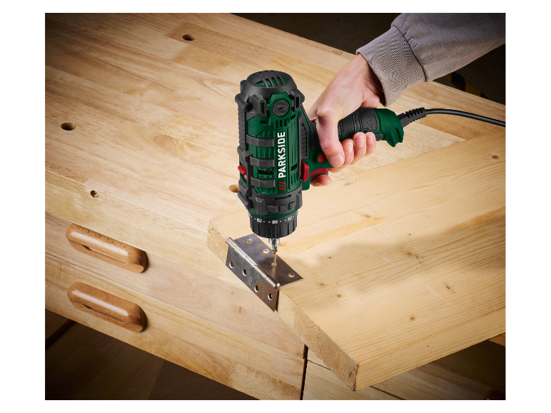 Eine Person verwendet einen Parkside Bohrer, um ein Scharnier an einem Holzbrett zu befestigen.