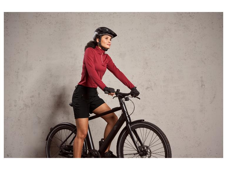 Eine Frau auf einem schwarzen Fahrrad mit Helm.