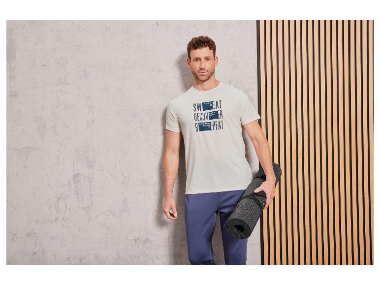 Mann in einem weißen T-Shirt ' 'mit Sportkleidung und einer Yogamatte.