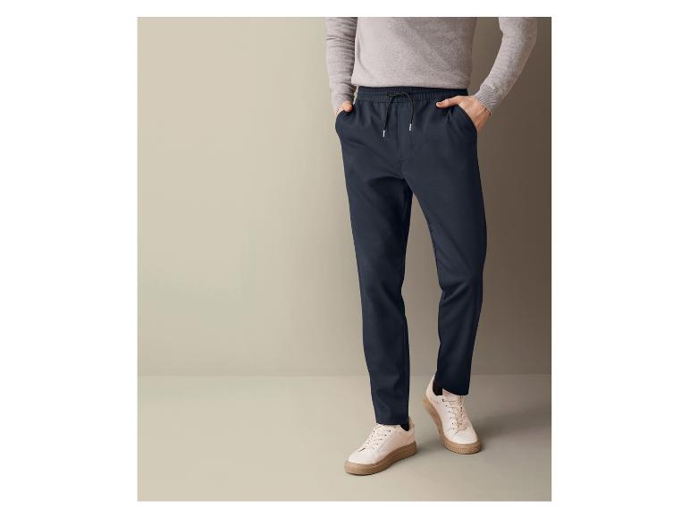 Ein Mann trägt dunkelblaue Hose mit Kordelzug und weiße Sneaker.