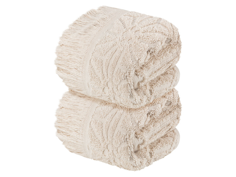 Zwei beige Handtücher mit Fransen.