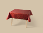 Rote Weihnachtstischdecke mit goldenen festlichen Mustern auf einem Holztisch.