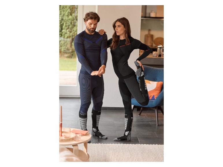 Zwei Personen in Sportunterwäsche und Socken dehnen sich drinnen.