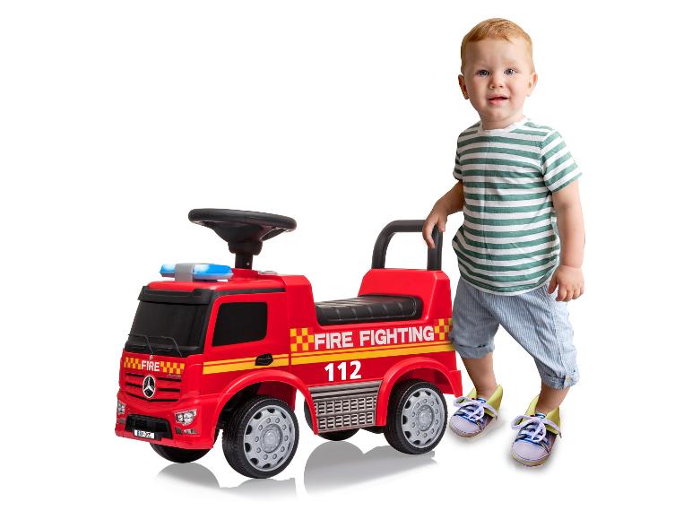 Kleinkind neben rotem Feuerwehrauto-Rutscher mit der Aufschrift „FIRE FIGHTING“ und der Nummer „112“.