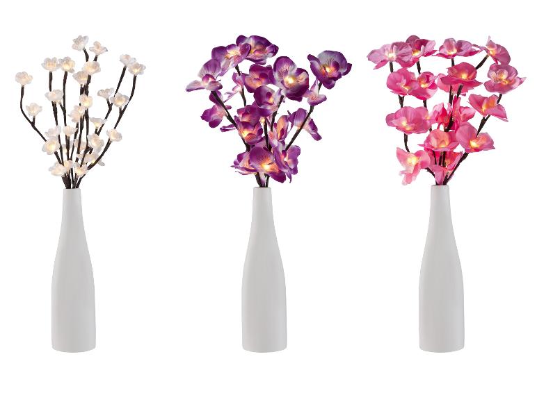 Drei weiße Vasen mit beleuchteten Blumen: weißen, lila und rosa.