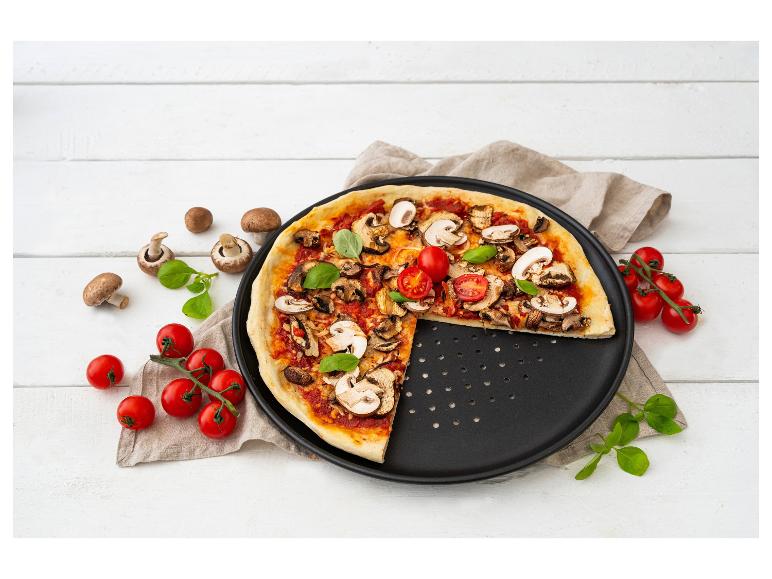 Pizza mit Champignons und Kirschtomaten auf einem Backblech.