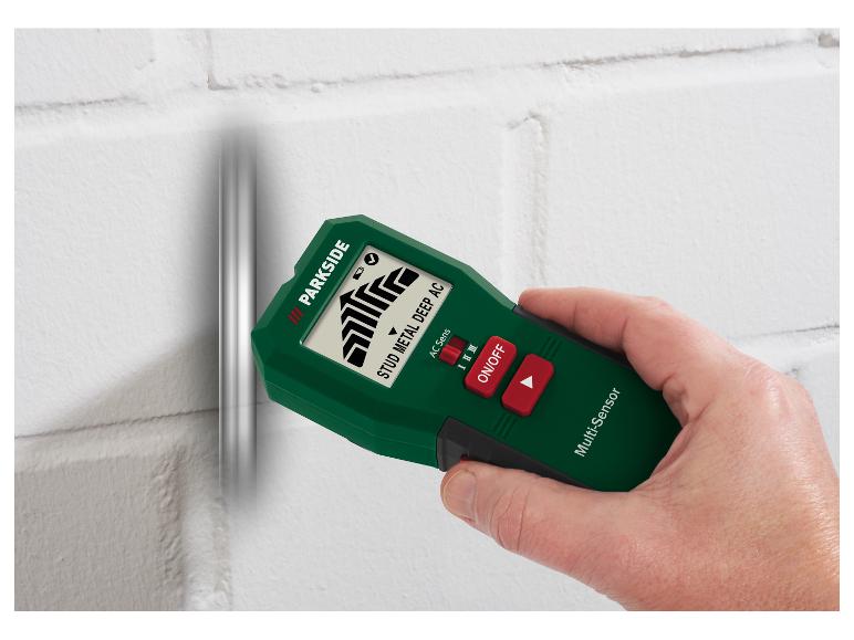 Grüner und schwarzer Multifunktions-Wanddetektor, von einer Hand gehalten, an einer weißen Wand.