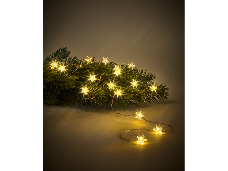 Sternförmige Lichterkette auf einem Tannenzweig, die festliche Stimmung erzeugt.