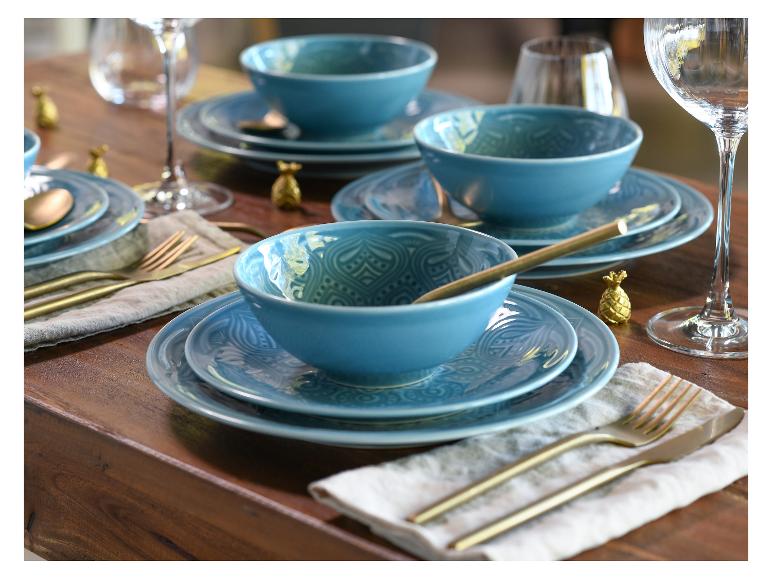 Blaue Schüsseln und Teller mit einem gravierten Muster auf einem Holztisch.