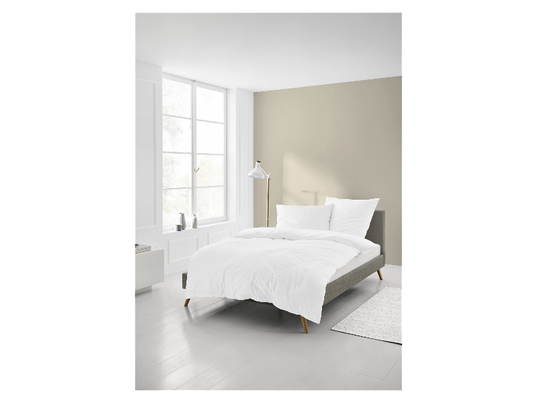 Bett, weiße Bettwäsche und Teppich in einem modernen Schlafzimmer.