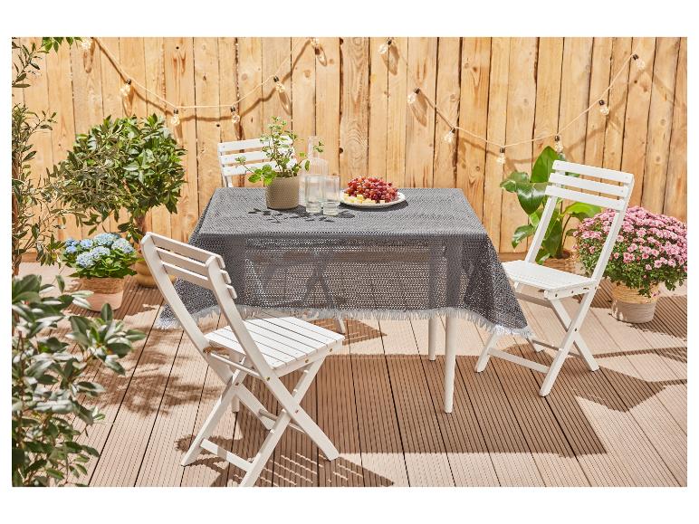 Weißer Klapptisch und -stühle, graue Tischdecke, Außenbereich.