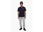 Mann in schwarzem T-Shirt, grauer Jogginghose, schwarzer Mütze und schwarzen Turnschuhen.