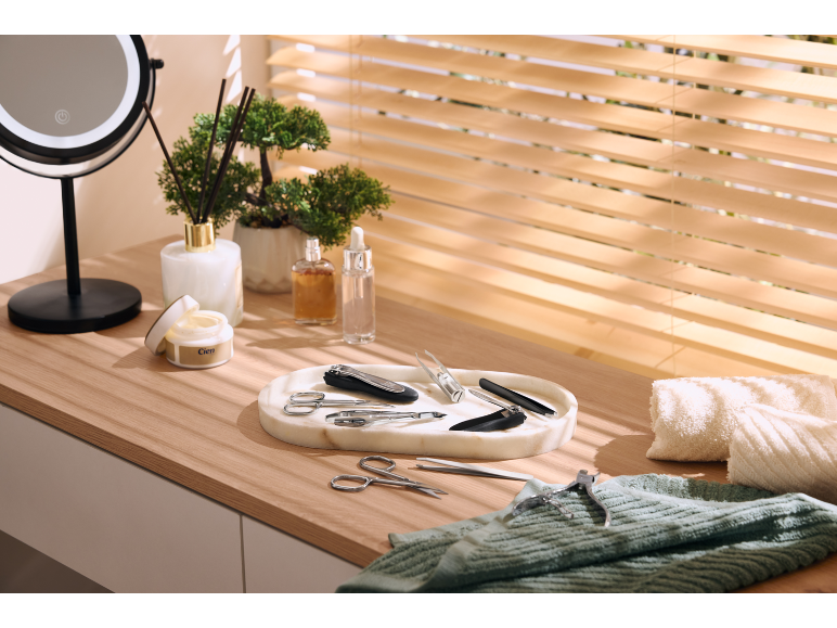 Maniküre-Set auf Marmortablett, mit Kosmetik und Spiegel auf einem Holzschminktisch.
